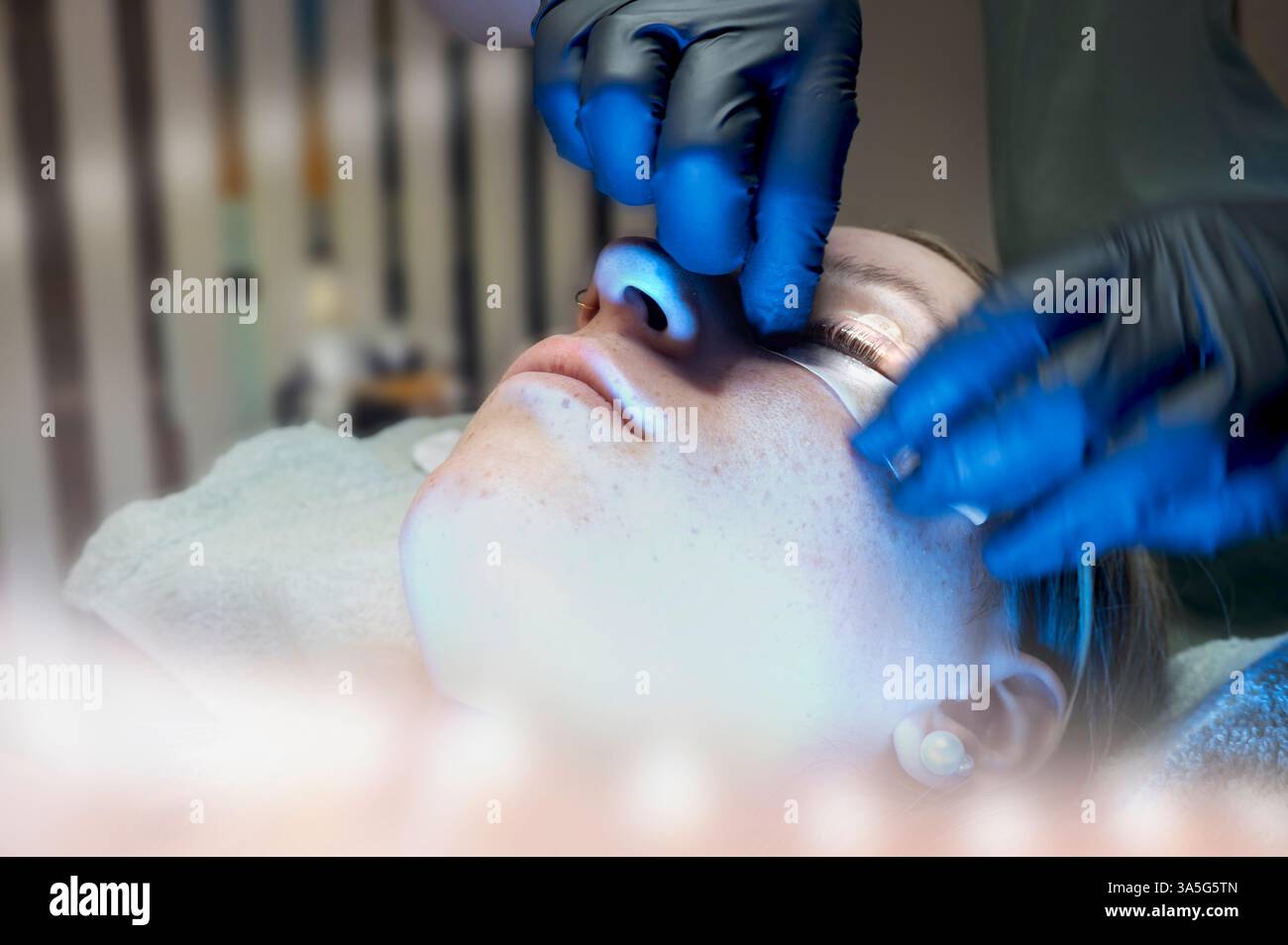 Primo piano di bellezza di una giovane donna che si solleva la ciglia con un sollevamento ciglia da parte di un estetista in un salone di bellezza. Dare forma alle sopracciglia. Foto Stock