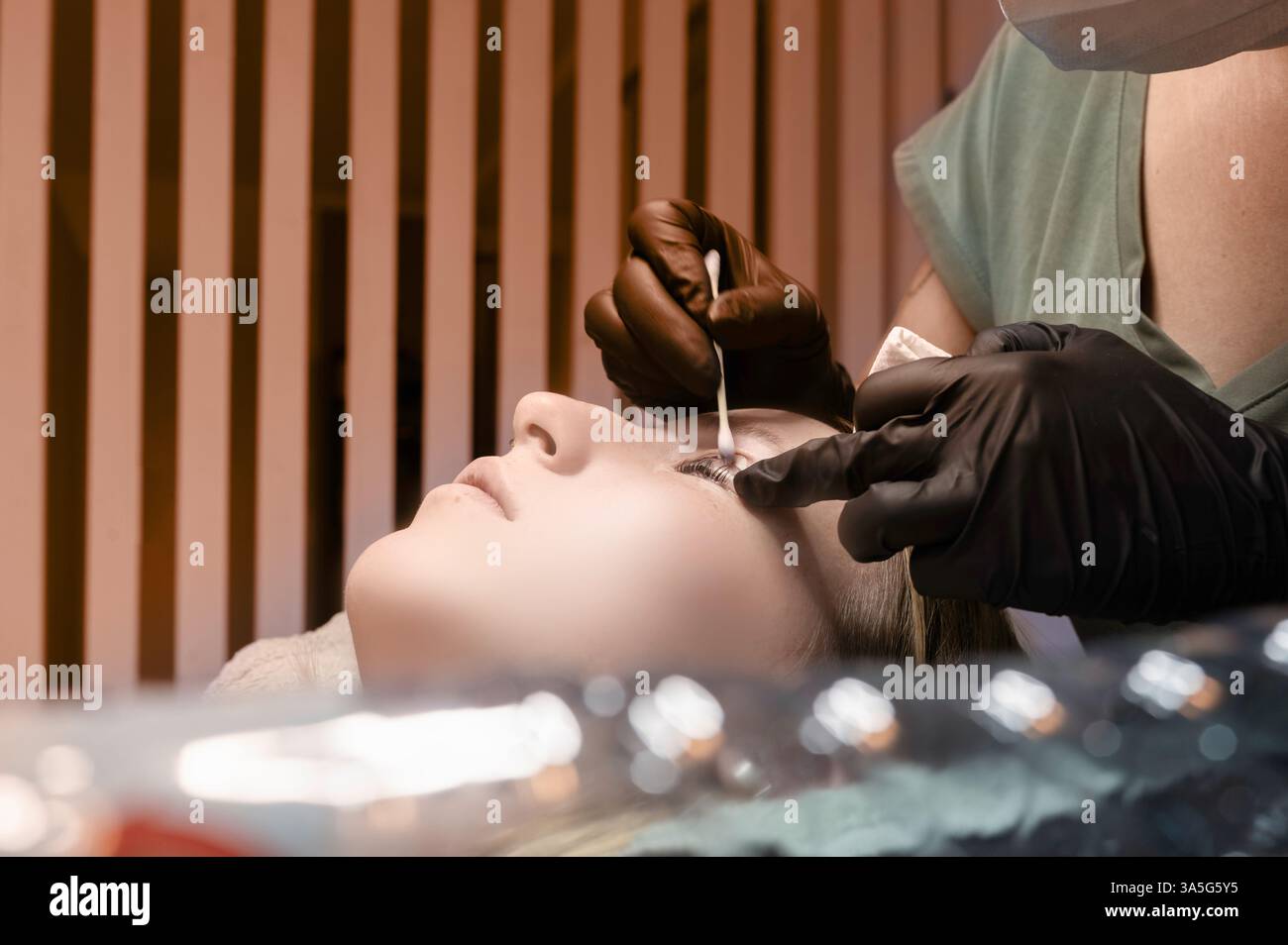 Primo piano di bellezza di una giovane donna che si solleva la ciglia con un sollevamento ciglia da parte di un estetista in un salone di bellezza. Dare forma alle sopracciglia. Foto Stock