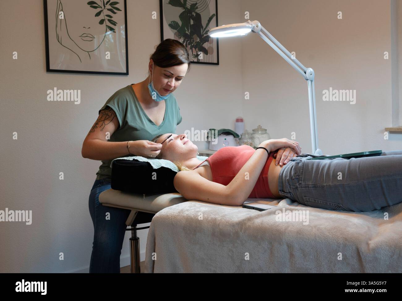 Primo piano di bellezza di una giovane donna che si solleva la ciglia con un sollevamento ciglia da parte di un estetista in un salone di bellezza. Dare forma alle sopracciglia. Foto Stock