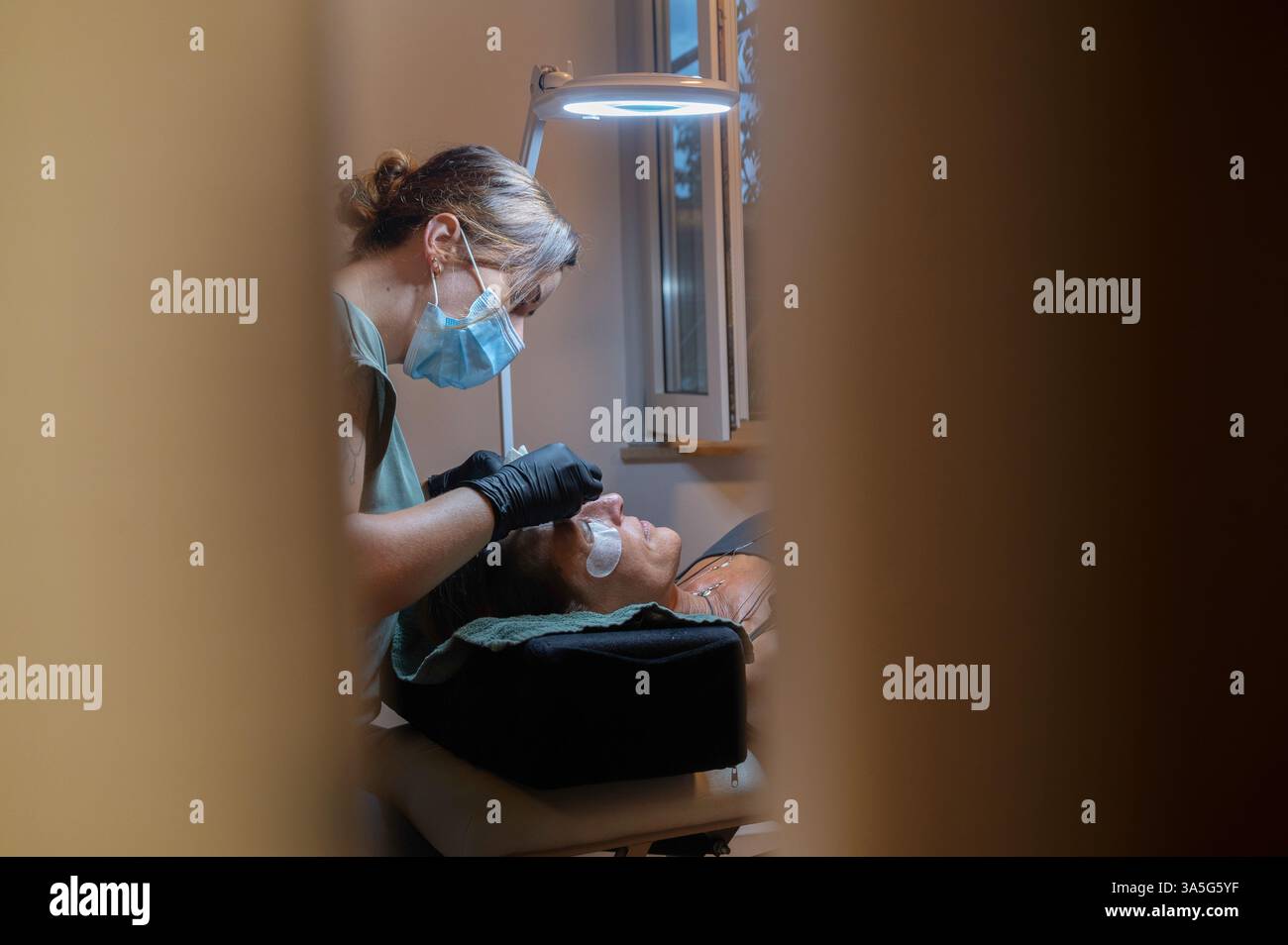 Primo piano di bellezza di una giovane donna che si solleva la ciglia con un sollevamento ciglia da parte di un estetista in un salone di bellezza. Dare forma alle sopracciglia. Foto Stock