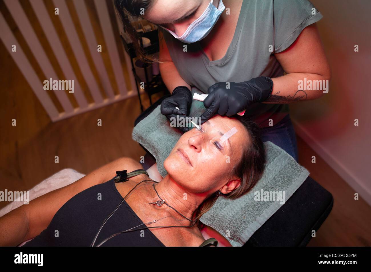 Primo piano di bellezza di una giovane donna che si solleva la ciglia con un sollevamento ciglia da parte di un estetista in un salone di bellezza. Dare forma alle sopracciglia. Foto Stock