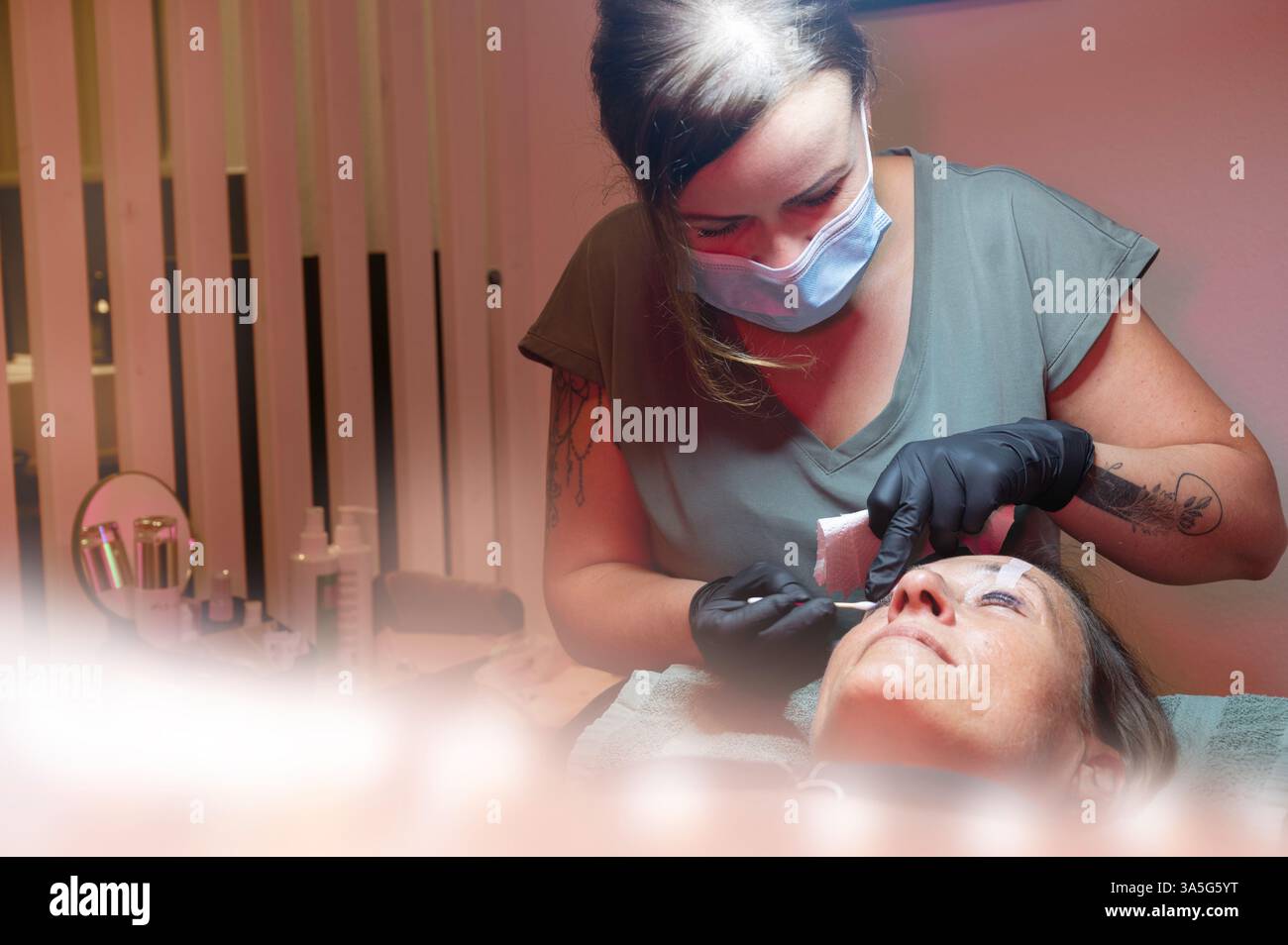 Primo piano di bellezza di una giovane donna che si solleva la ciglia con un sollevamento ciglia da parte di un estetista in un salone di bellezza. Dare forma alle sopracciglia. Foto Stock