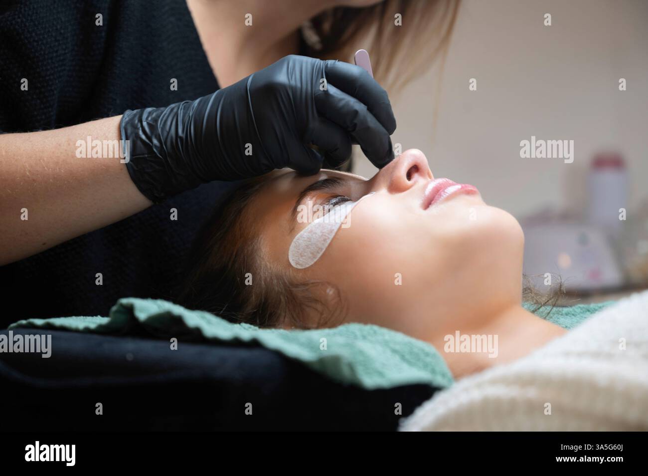Primo piano di bellezza di una giovane donna che si solleva la ciglia con un sollevamento ciglia da parte di un estetista in un salone di bellezza. Dare forma alle sopracciglia. Foto Stock