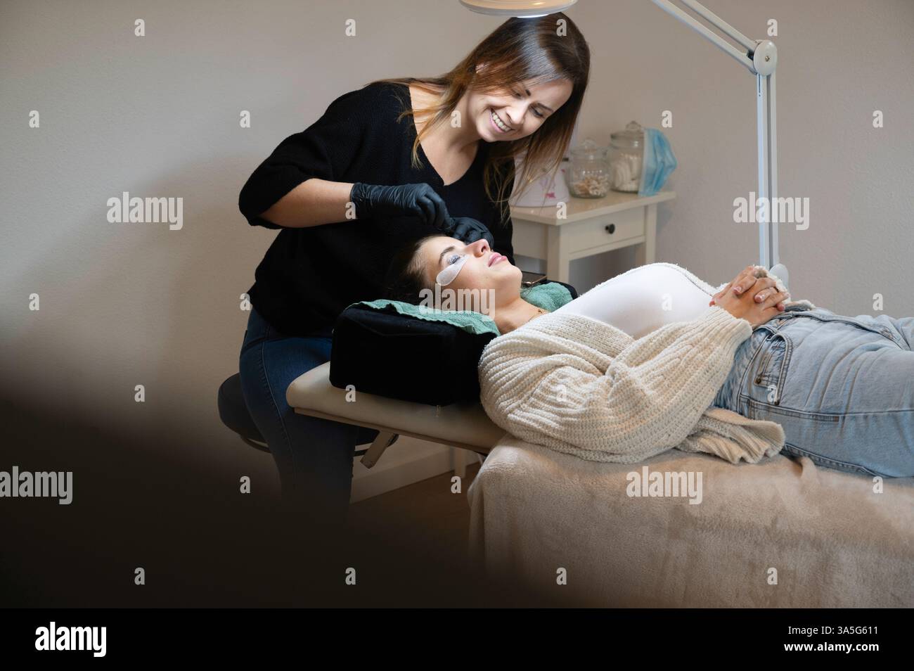 Primo piano di bellezza di una giovane donna che si solleva la ciglia con un sollevamento ciglia da parte di un estetista in un salone di bellezza. Dare forma alle sopracciglia. Foto Stock