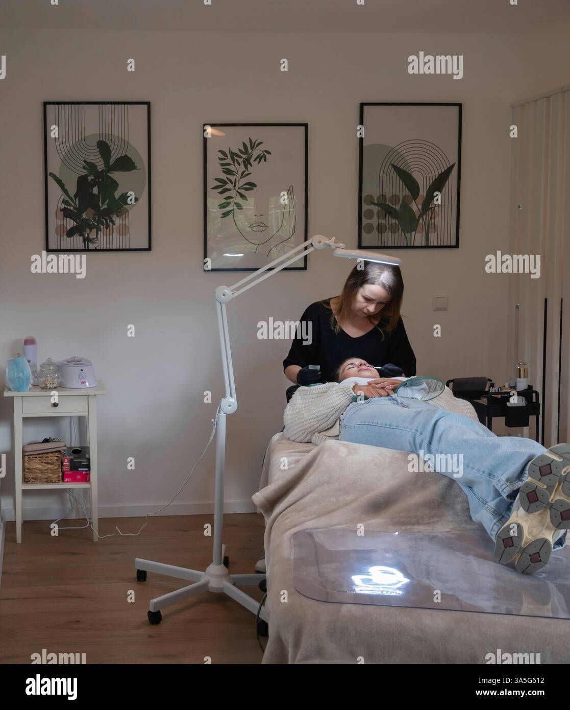 Primo piano di bellezza di una giovane donna che si solleva la ciglia con un sollevamento ciglia da parte di un estetista in un salone di bellezza. Dare forma alle sopracciglia. Foto Stock