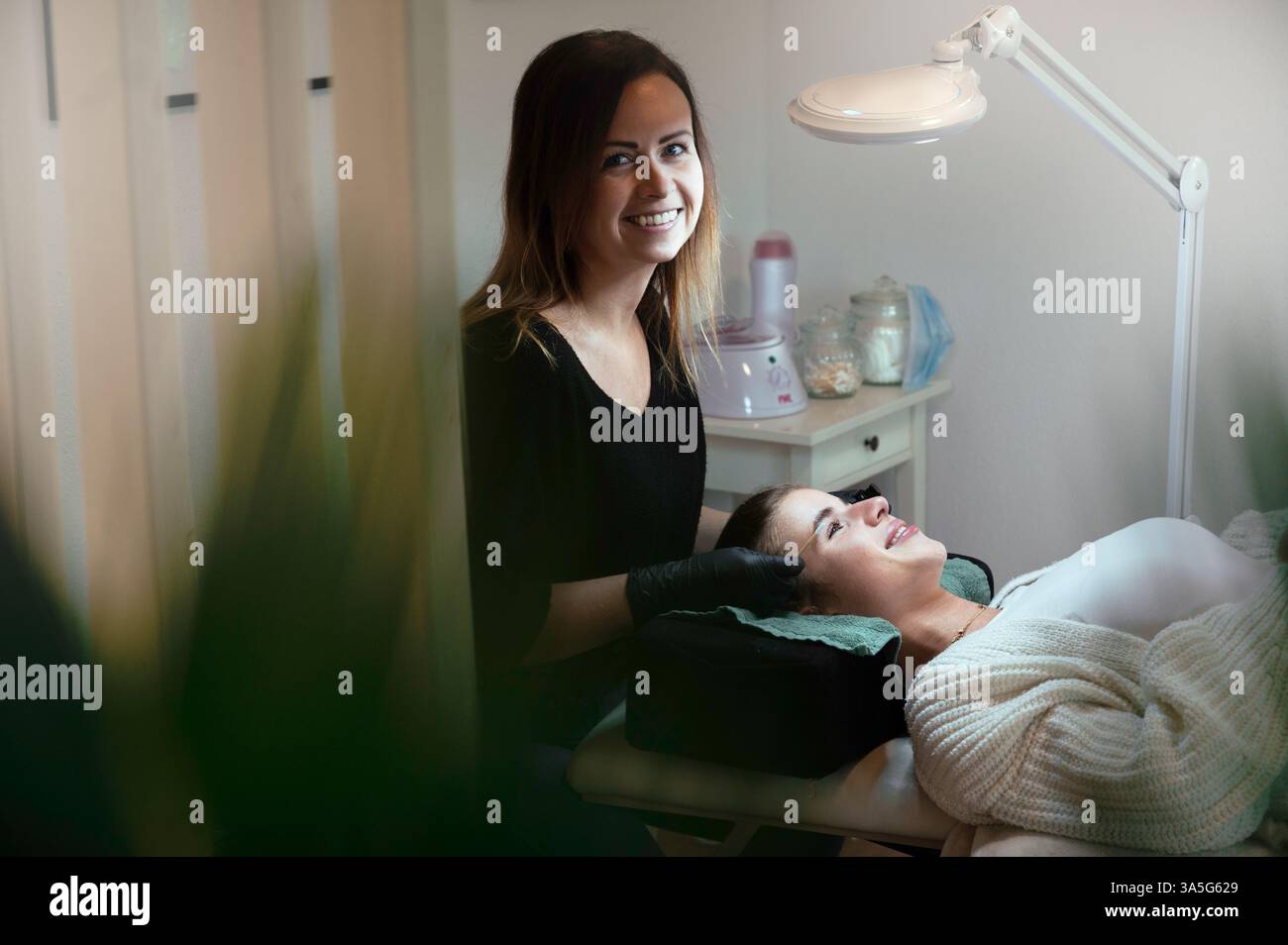 Primo piano di bellezza di una giovane donna che si solleva la ciglia con un sollevamento ciglia da parte di un estetista in un salone di bellezza. Dare forma alle sopracciglia. Foto Stock