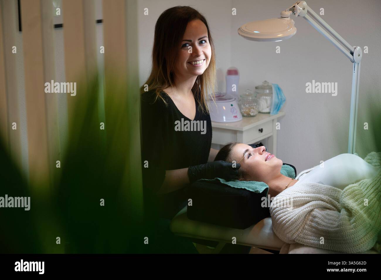 Primo piano di bellezza di una giovane donna che si solleva la ciglia con un sollevamento ciglia da parte di un estetista in un salone di bellezza. Dare forma alle sopracciglia. Foto Stock