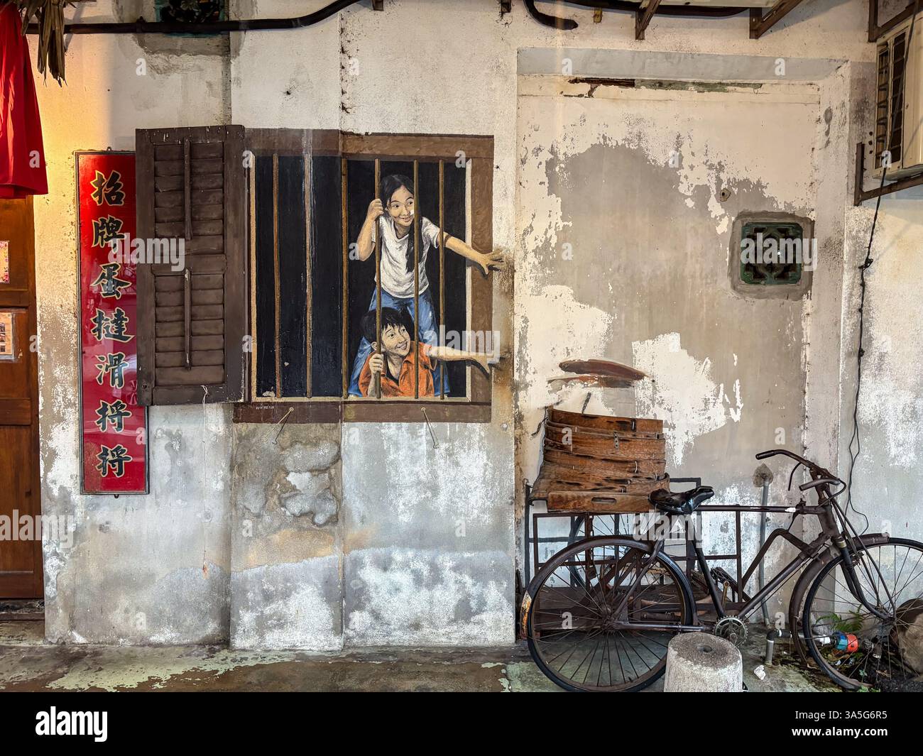 Street art raffigurante bambini a una finestra. Una vecchia bicicletta si appoggia contro la parete intemprata. George Town, Penang, Malesia. Foto Stock