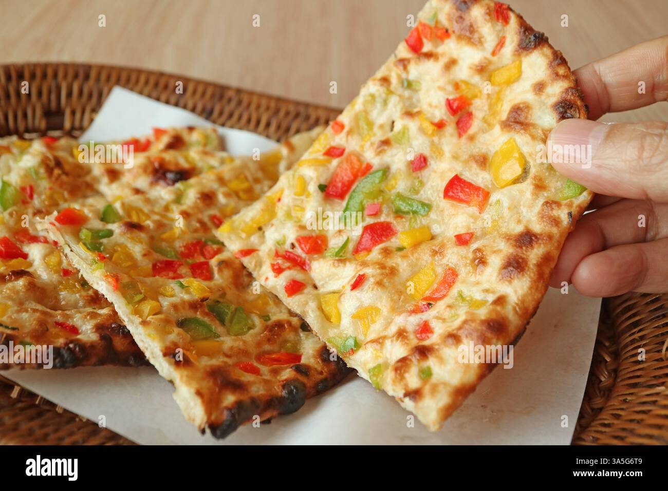 Scegliere a mano una fetta di Chili Naan dal cestino di vimini Foto Stock