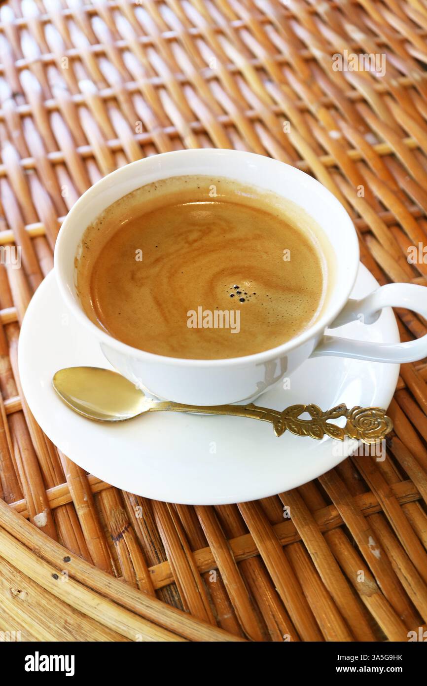 Una tazza di caffè caldo appena fatto isolato sul tavolo di rattan Foto Stock