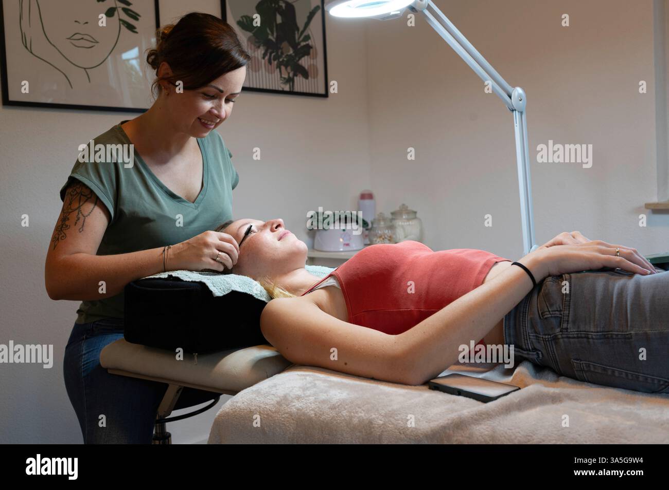 Primo piano di bellezza di una giovane donna che si solleva la ciglia con un sollevamento ciglia da parte di un estetista in un salone di bellezza. Dare forma alle sopracciglia. Foto Stock