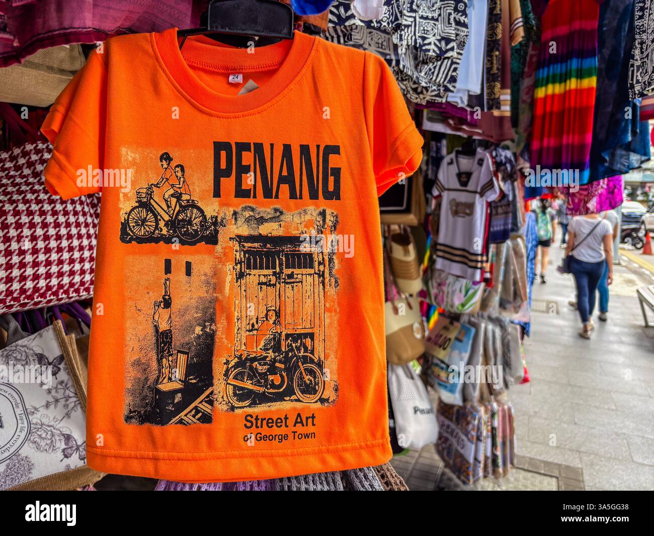 Una t-shirt arancione in vendita che recita "Penang" con il design "Street Art of George Town". Foto Stock