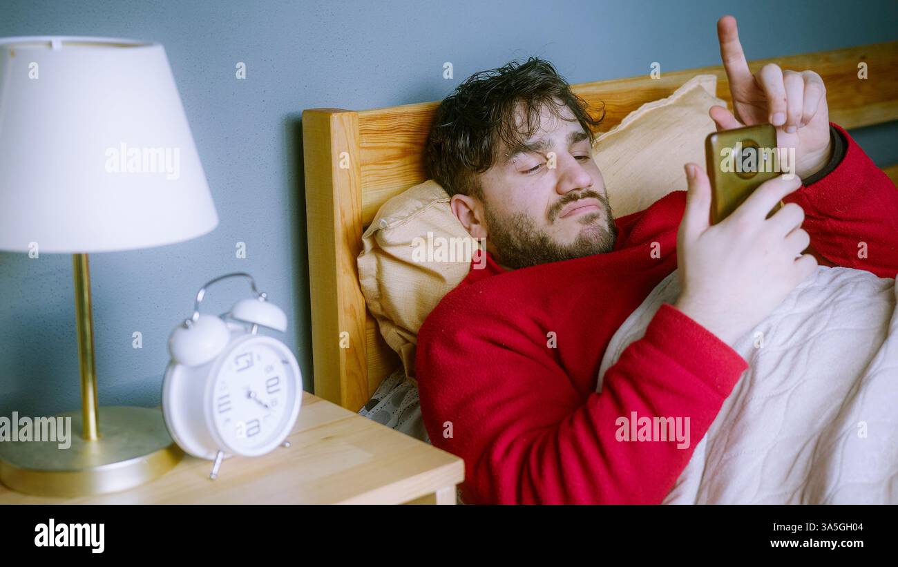 Svegliarsi e raggiungere immediatamente il telefono, scorrere all'infinito i brevi video e perdere traccia del tempo Foto Stock