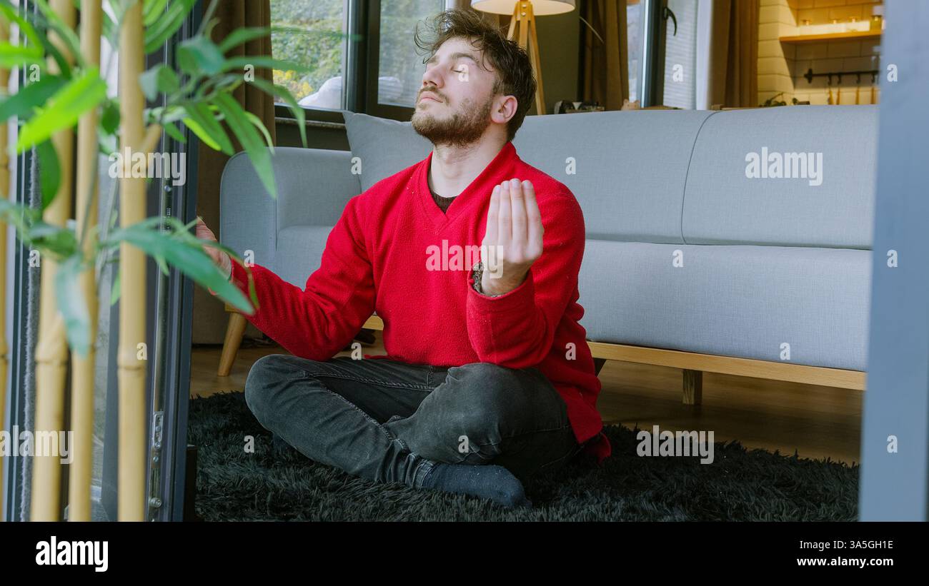 Uomo che pratica la meditazione sulla mentalità a casa in un ambiente tranquillo: Relax, stress Relief e equilibrio interiore Foto Stock