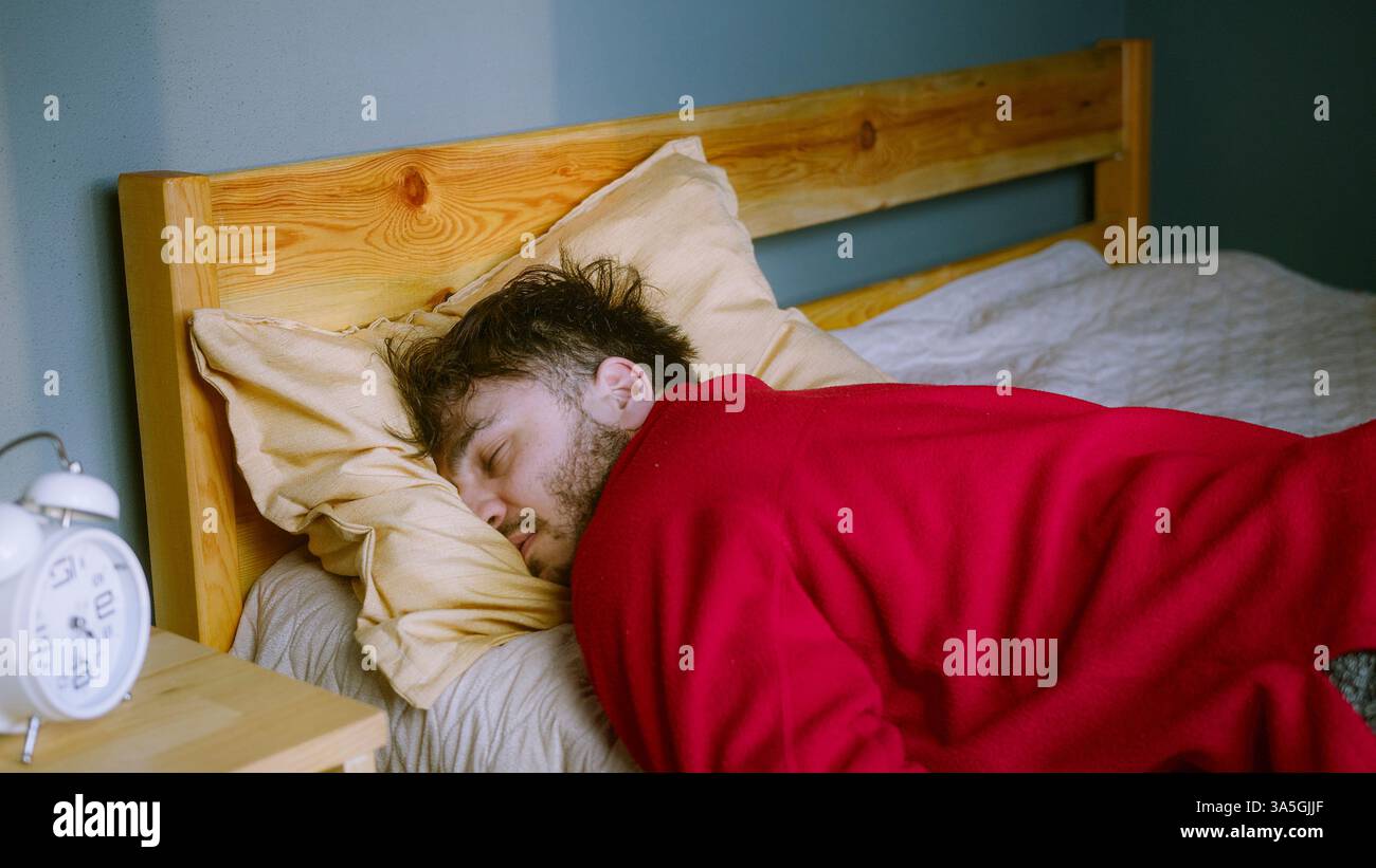 Uomo che dorme in pace a letto – sonno profondo o riposo stanco Foto Stock