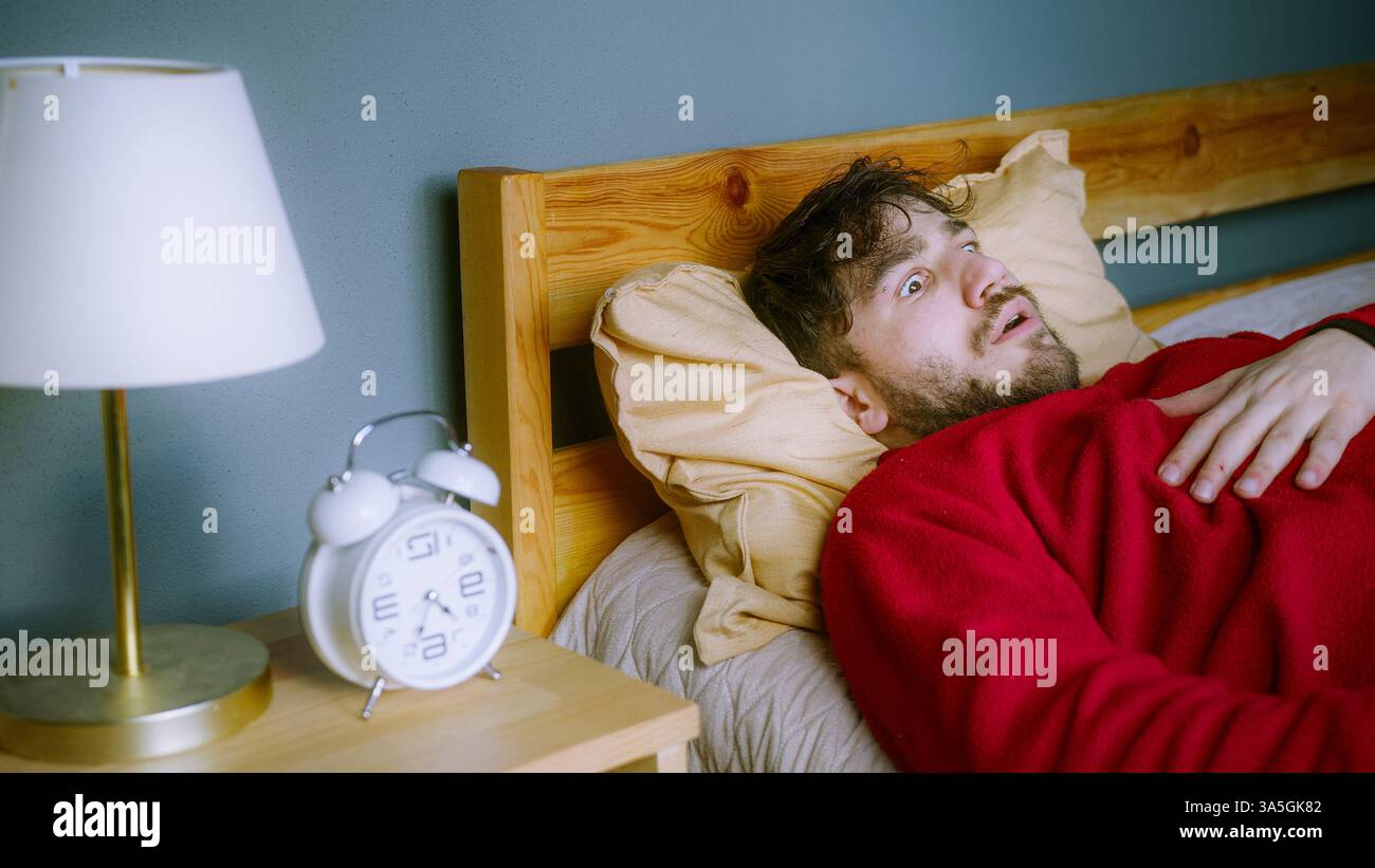 Uomo che si sveglia in shock dopo un incubo – paralisi del sonno o reazione di apnea del sonno Foto Stock