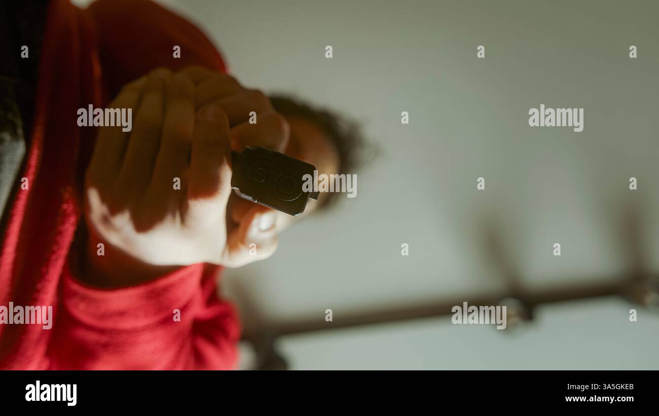 Primo piano spettacolare di una persona che punta una pistola nera direttamente verso la fotocamera e spara in una scena intensa e poco illuminata Foto Stock