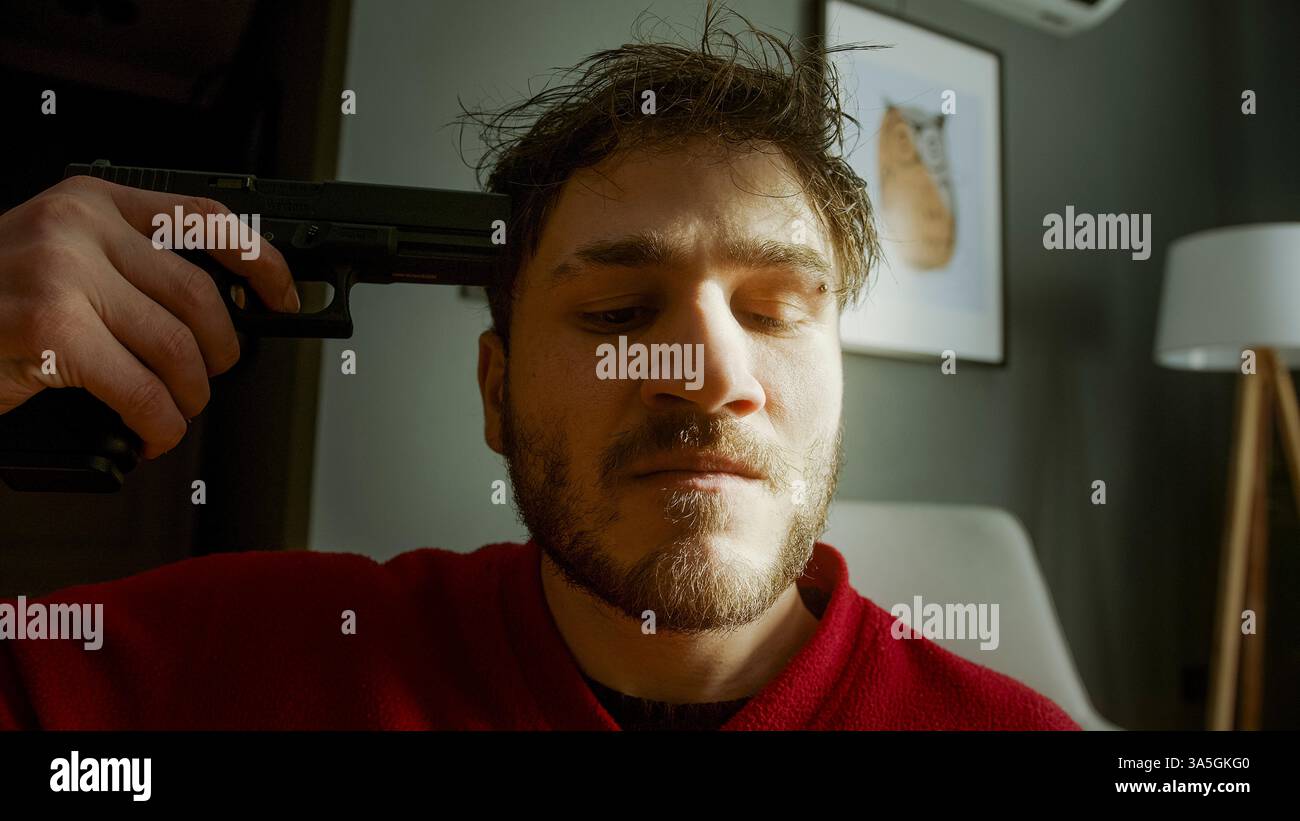 Primo piano di un uomo in difficoltà che tiene una pistola alla testa in Dramatic Lighting - concetto di disperazione, depressione e lotta interiore Foto Stock