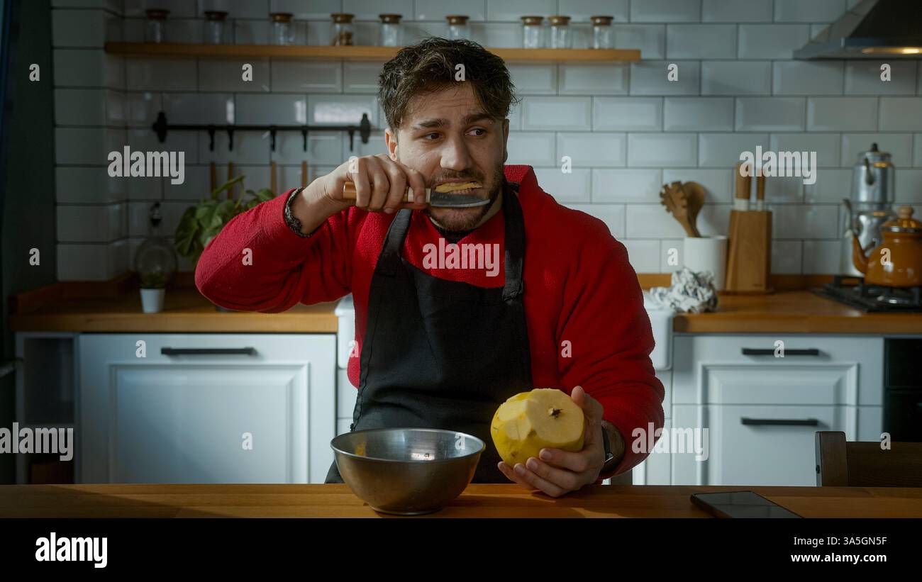Uomo che assaggia una cotogna in cucina con un'espressione giocosa e divertente Foto Stock