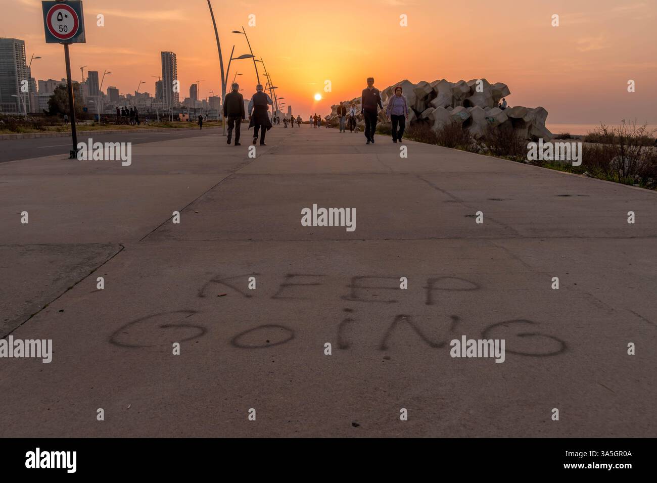 La parola "continua" sulla strada nella città di Beirut, la capitale del Libano, Medio Oriente, con la gente del posto che si gode la serata. Foto Stock