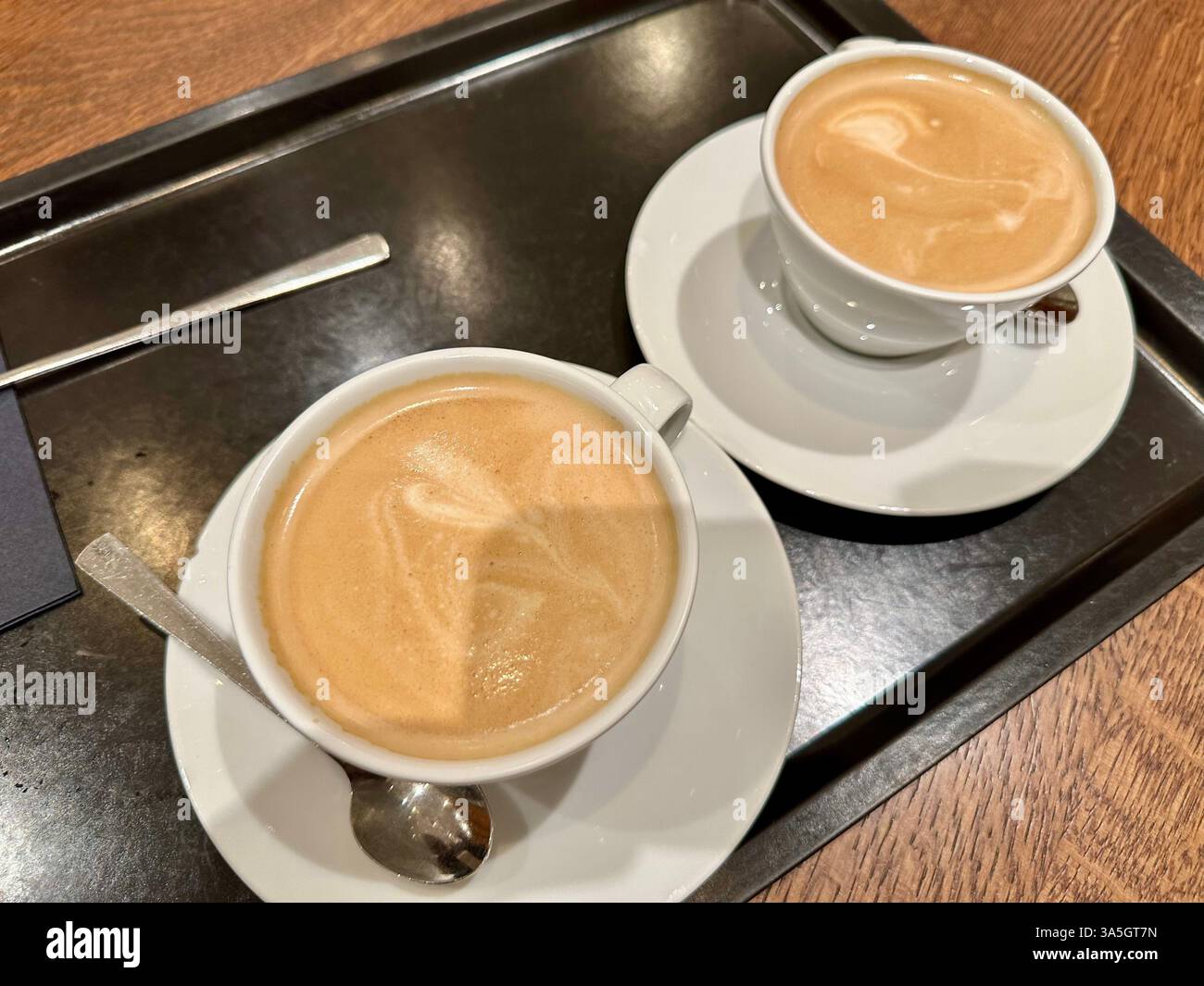 Due tazze di bianco piatto su un vassoio nero Foto Stock