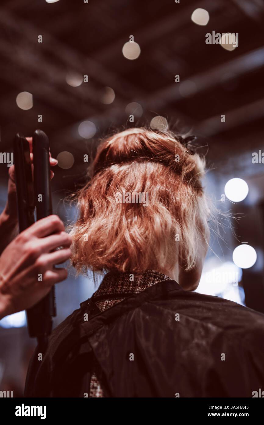 Le mani femminili di un parrucchiere lisciano i capelli corti con uno styler professionale caldo Foto Stock