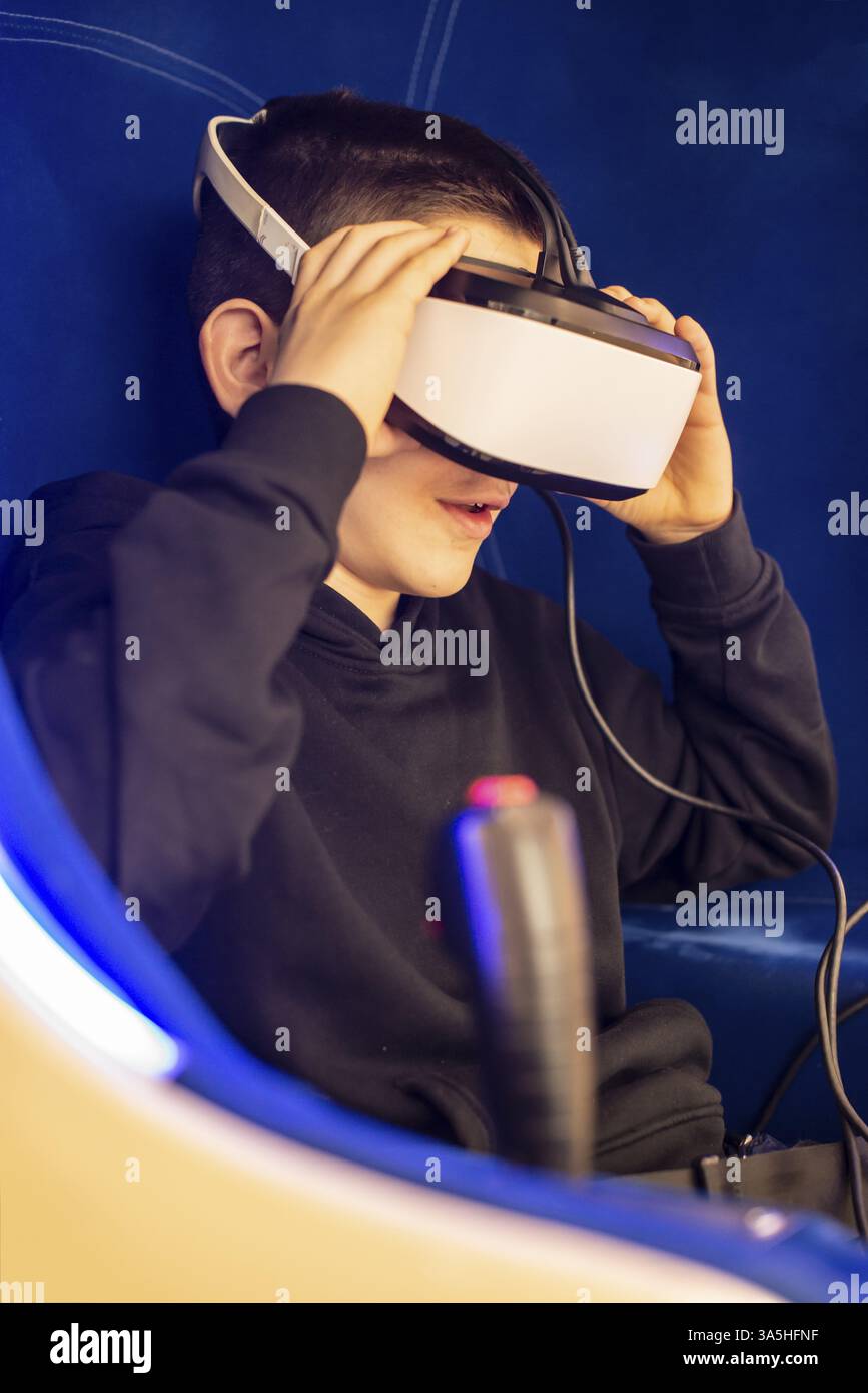 Bambino guardando film con occhiali VR. Blu cabina illuminata con il joystick. Effetti speciali. Tecnologia e concetto di intrattenimento con realit virtuale Foto Stock
