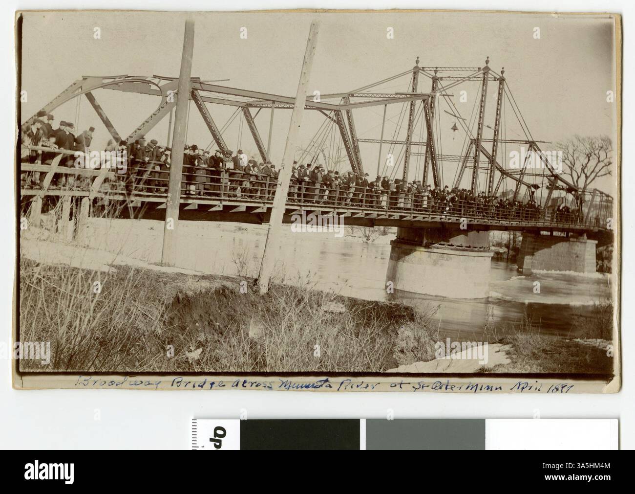 Una fotografia del Broadway Bridge sul fiume Minnesota a St. Peter, scattata nell'aprile 1897 durante un'alluvione. L'immagine mostra le persone in piedi sul ponte con elevatori di grano visibili in lontananza. Foto Stock