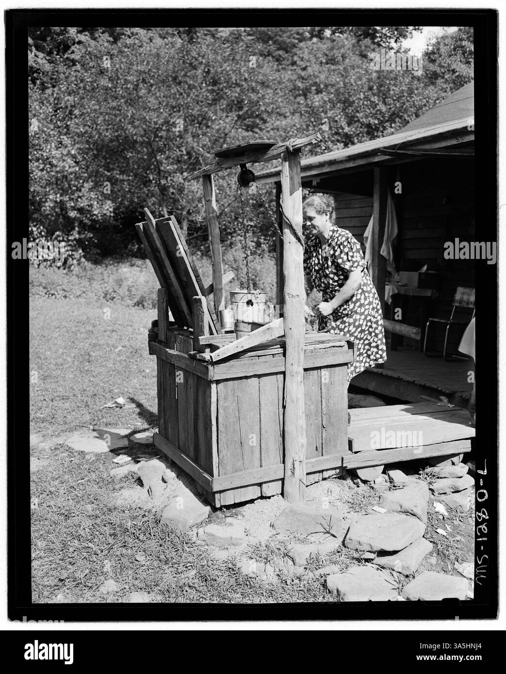 La famiglia inglese attinge l'acqua da un pozzo nella fattoria durante la riunione annuale a Hensley Hollow, contea di McDowell, West Virginia. Questo cattura un momento di vita rurale nella regione degli Appalachi. Foto Stock
