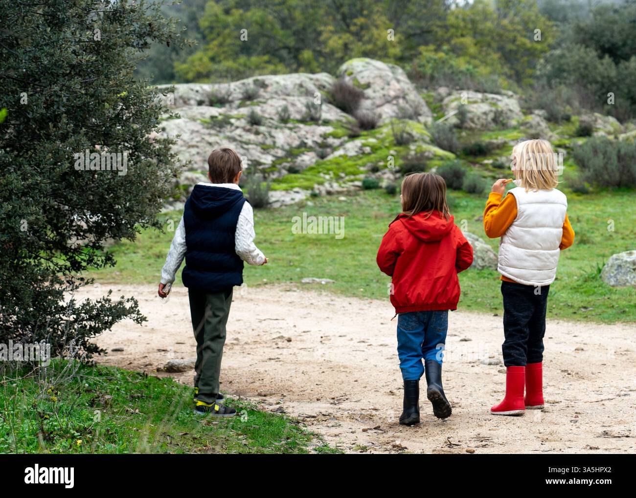 Tre bambini che camminano attraverso la natura in autunno Foto Stock