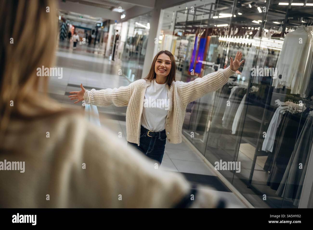 Due donne si incontrano al centro commerciale, si abbracciano, gesto di saluto. Foto Stock