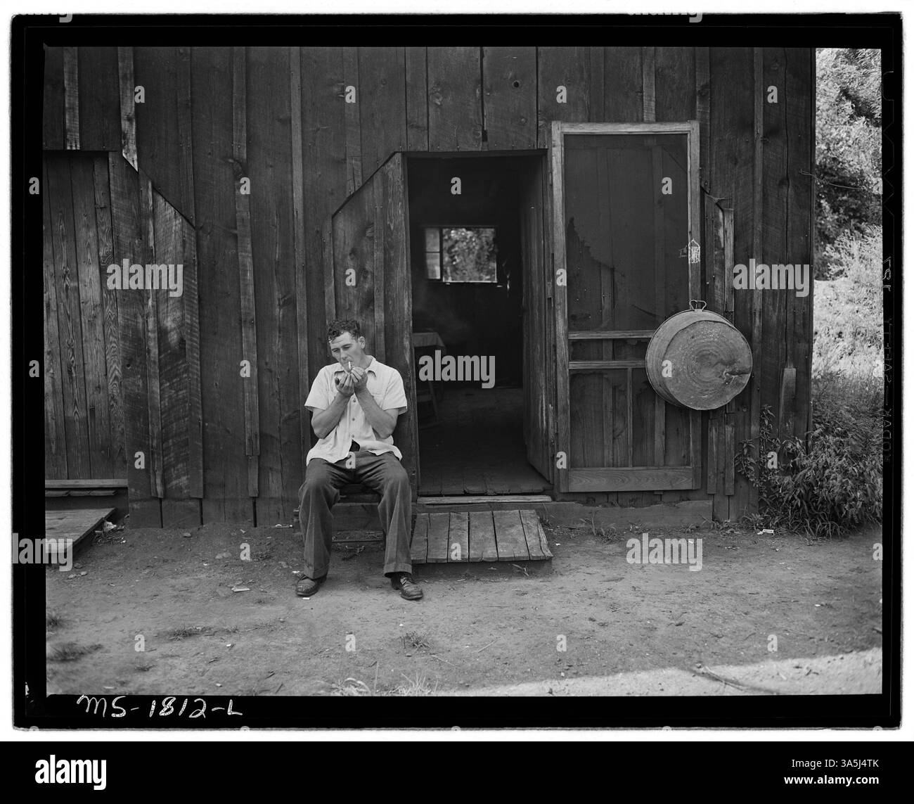 Ray Boggess, un minatore, siede di fronte a un garage convertito che funge da suo spazio abitativo a Mullens, Wyoming County, West Virginia. Lo spazio è grande circa quanto un garage per un'auto, e lui paga 5,30 dollari al mese, che include l'elettricità. Ciò riflette le condizioni abitative di alcuni minatori in progetti immobiliari aziendali. Archivi nazionali al College Park - Still Pictures. Foto Stock