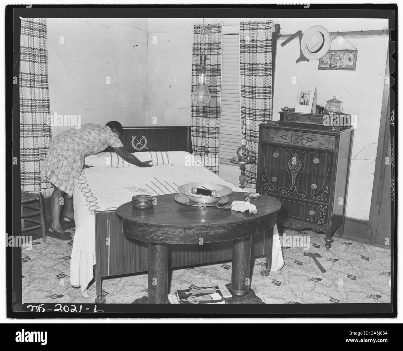 Questa immagine mostra la signora Robert Harold nella camera da letto al piano inferiore della sua casa a Bradshaw, West Virginia. Gli Harolds hanno vissuto nella casa per sedici anni, pagando un basso affitto di $ 11 al mese, con costi aggiuntivi per le utenze. Il signor Harold ha completato lui stesso le riparazioni e i miglioramenti. Foto Stock