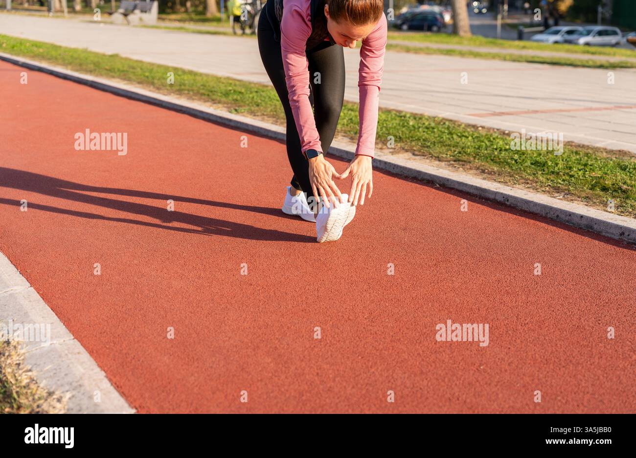 La runner si scalda su una pista da corsa in una strada cittadina Foto Stock