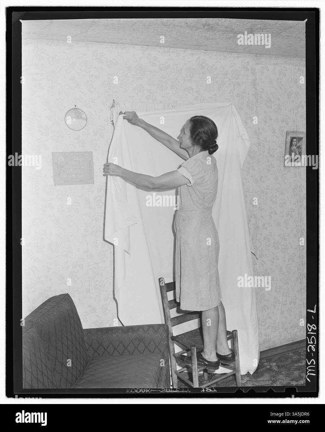 La signora Sergent alla miniera Clover Gap Mine nella contea di Harlan, Kentucky, impicca un foglio per separare suo marito mentre si bagna nella loro casa. Questa pratica evidenzia le condizioni di vita ravvicinate nei campi minerari. Foto Stock
