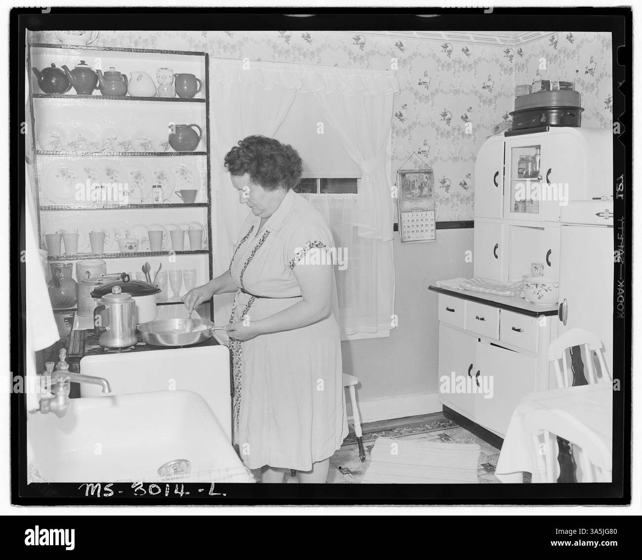 La signora Harry Fain, moglie di un caricatore di carbone, prepara la colazione mettendo il lardo in una padella nella loro casa vicino alle Wheelwright Mines della Inland Steel Company nella contea di Floyd, Kentucky. Questa immagine cattura un momento di vita domestica in una famiglia mineraria. Foto Stock