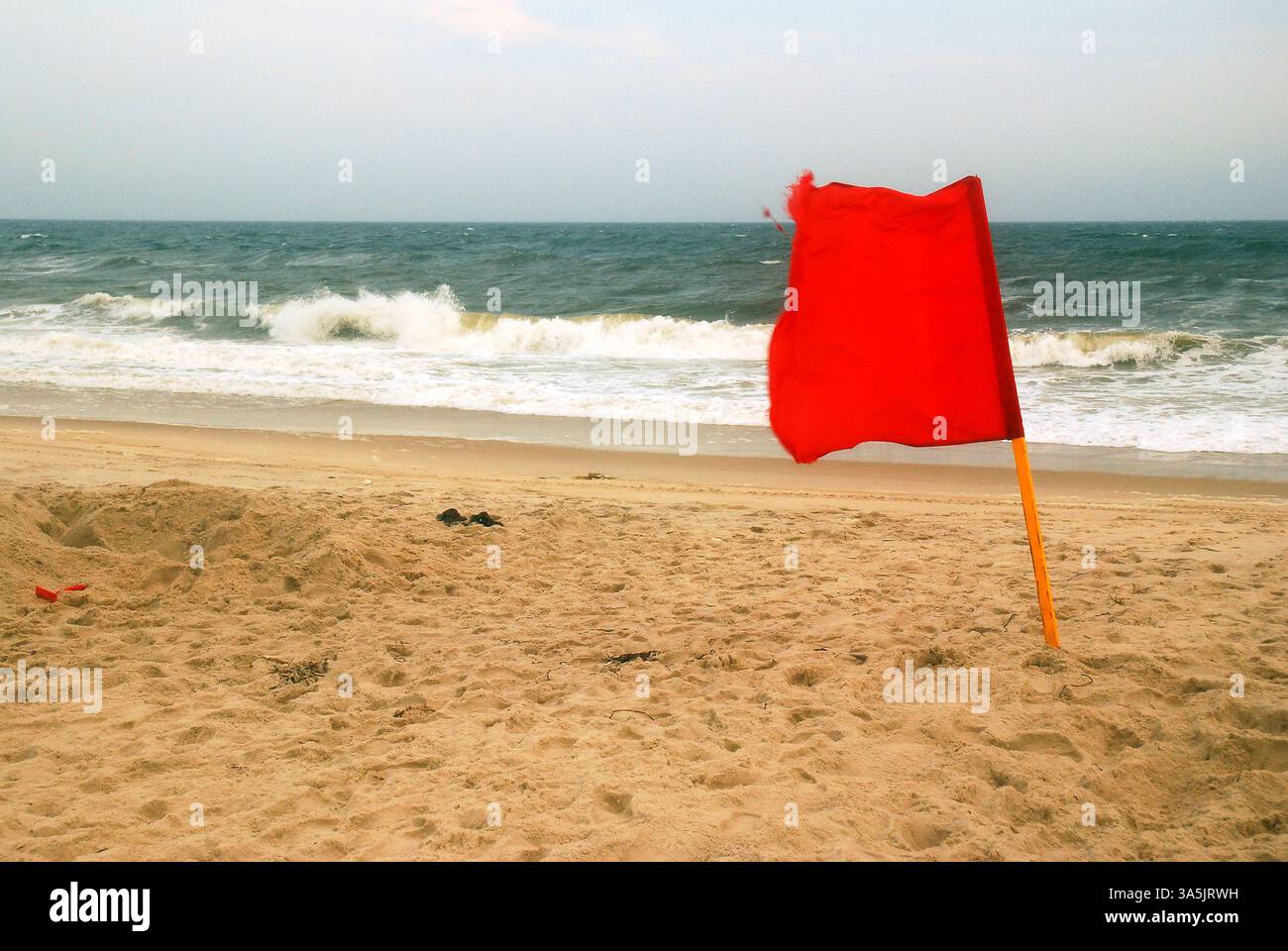 Una bandiera rossa avverte i nuotatori che non entrano nell'oceano a causa delle onde Foto Stock