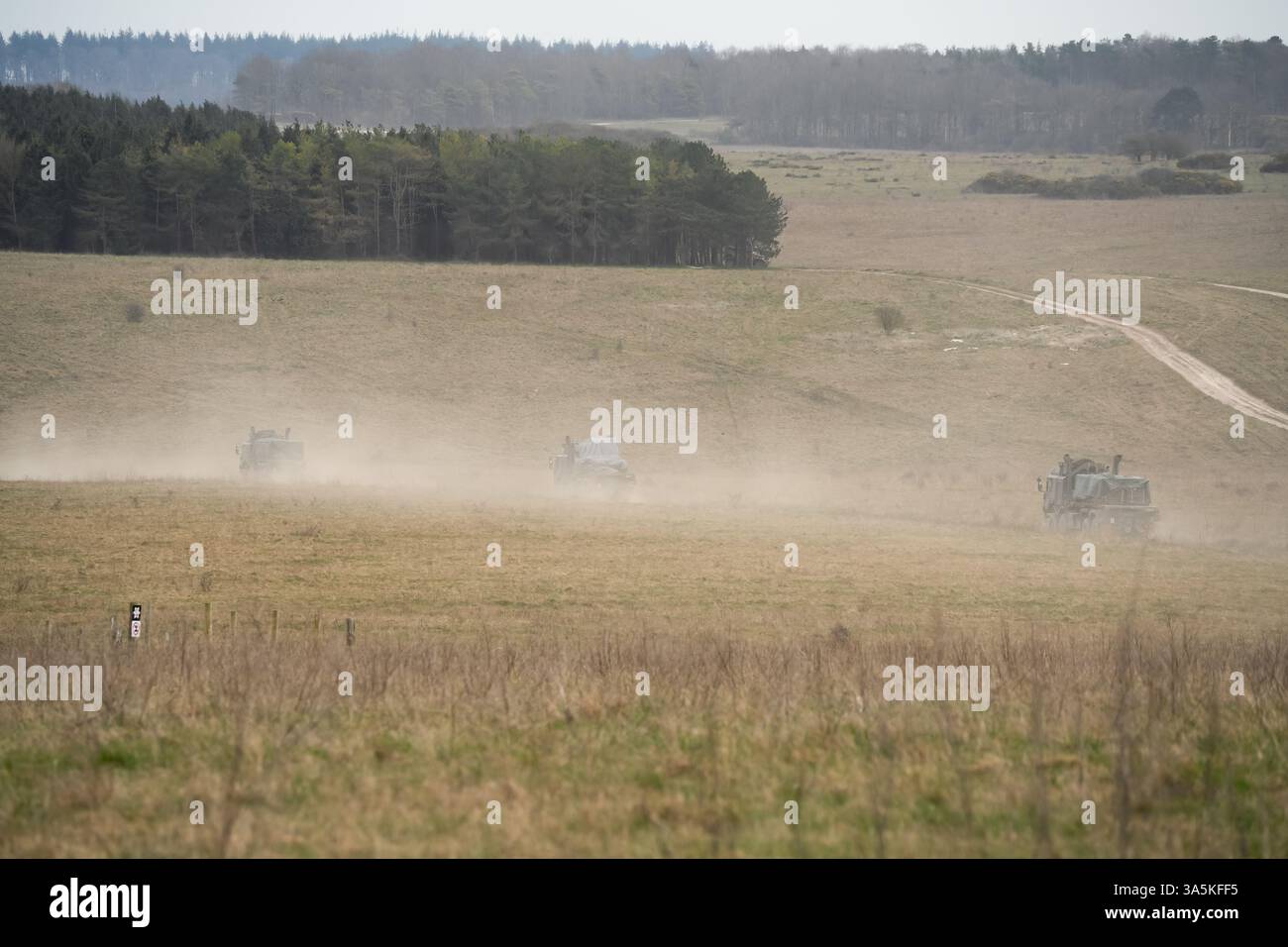 Convoglio dell'esercito britannico HX77 8x8 EPLS Heavy Utility Truck che trasporta rifornimenti in campagna, gettando polvere Foto Stock