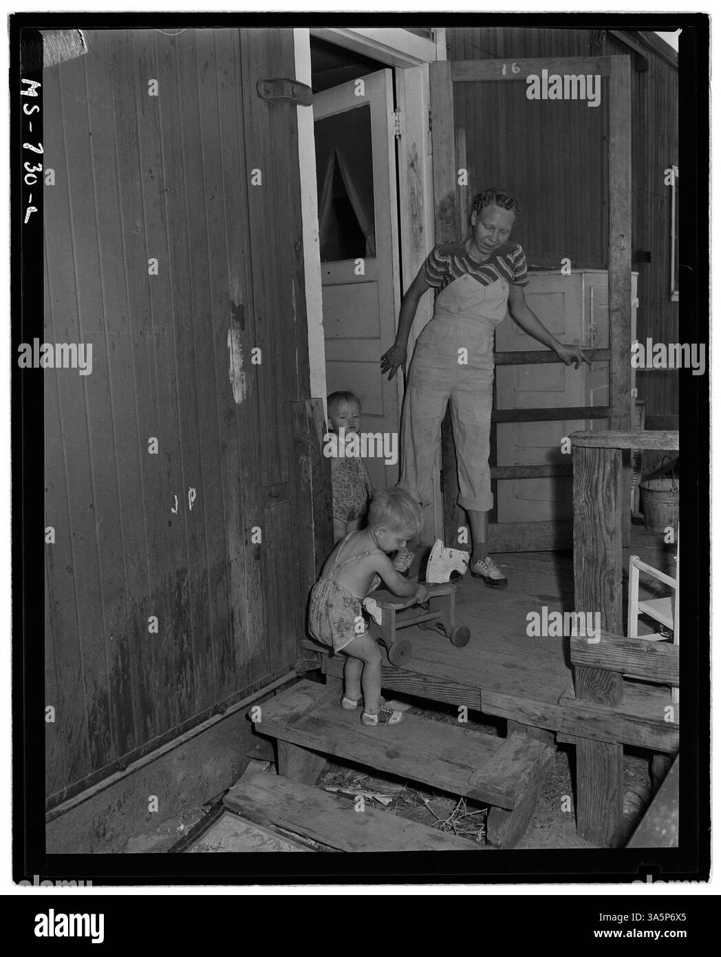 Questa immagine mostra la signora Jack Price e i suoi due figli sul portico del loro box car di casa, parte del progetto di case della Union Pacific Coal Company presso la Reliance Mine in Wyoming. Il box car è montato su una base di cemento per garantire stabilità. Foto Stock