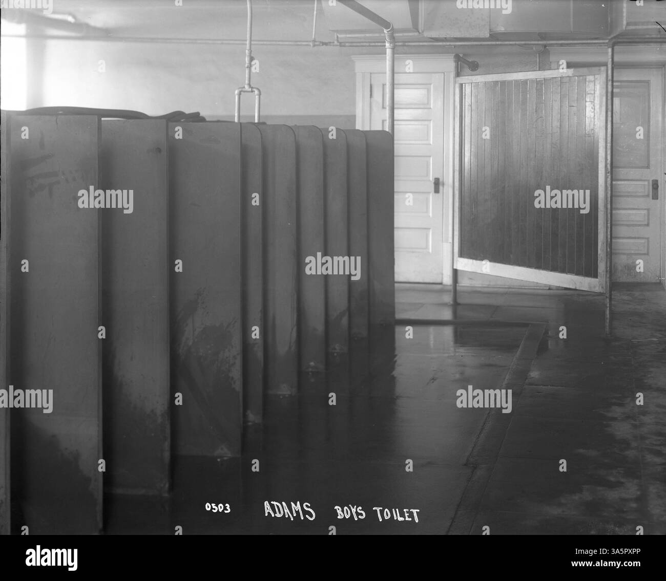 Una fotografia raffigurante gli orinatoi nel bagno della Adams School, che mostra il design degli interni delle strutture della scuola. L'immagine fornisce un'occhiata all'ambiente scolastico quotidiano durante il tempo. Foto Stock