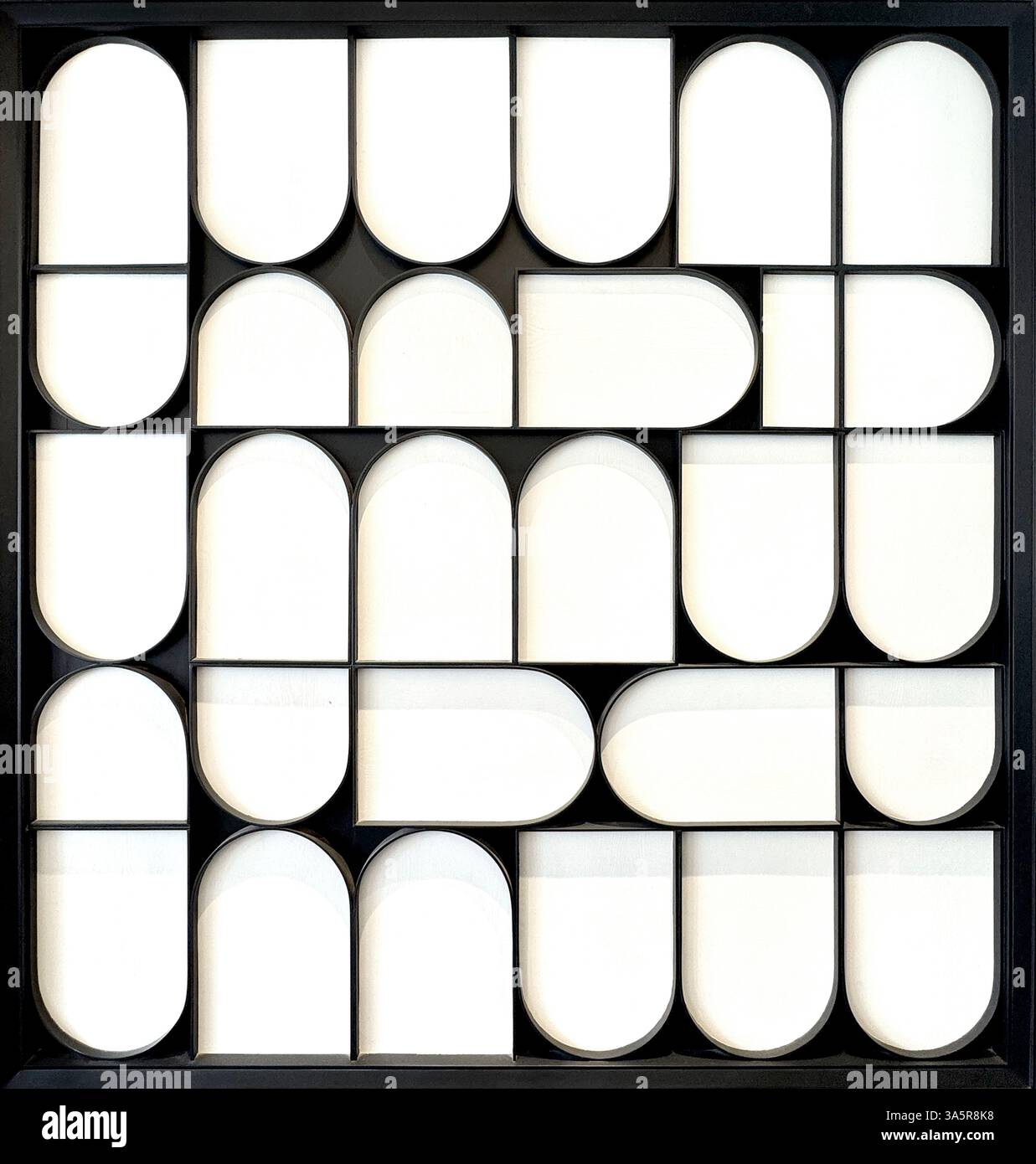 Primo piano di forme arrotondate casuali geometriche realizzate in compensato verniciato nero con ritaglio 3d tagliato al laser, con sfondo bianco. Testo in background senza interruzioni Foto Stock