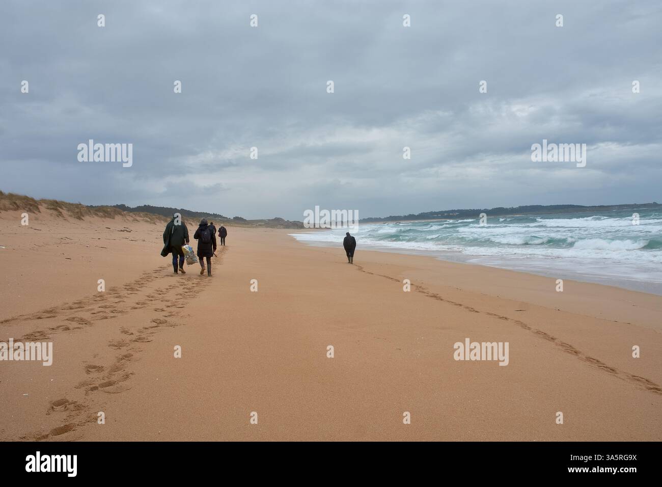 Corrubedo, Galizia, Spagna; 11 febbraio 2025: Un gruppo di individui cammina lungo la spiaggia di Vilar a Corrubedo, Galizia, Spagna, dopo aver osservato vari uccelli Foto Stock