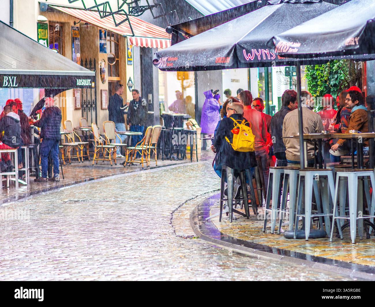 Persone che si proteggono dalla pioggia sotto le tettoie dei bar più famosi di Bruxelles, Belgio. Foto Stock