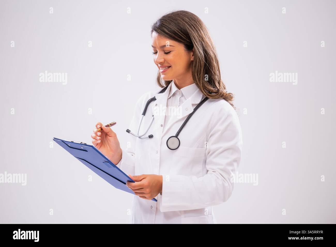Studio ha scattato un ritratto di una dottoressa felice che tiene in mano gli appunti e scrive. Foto Stock