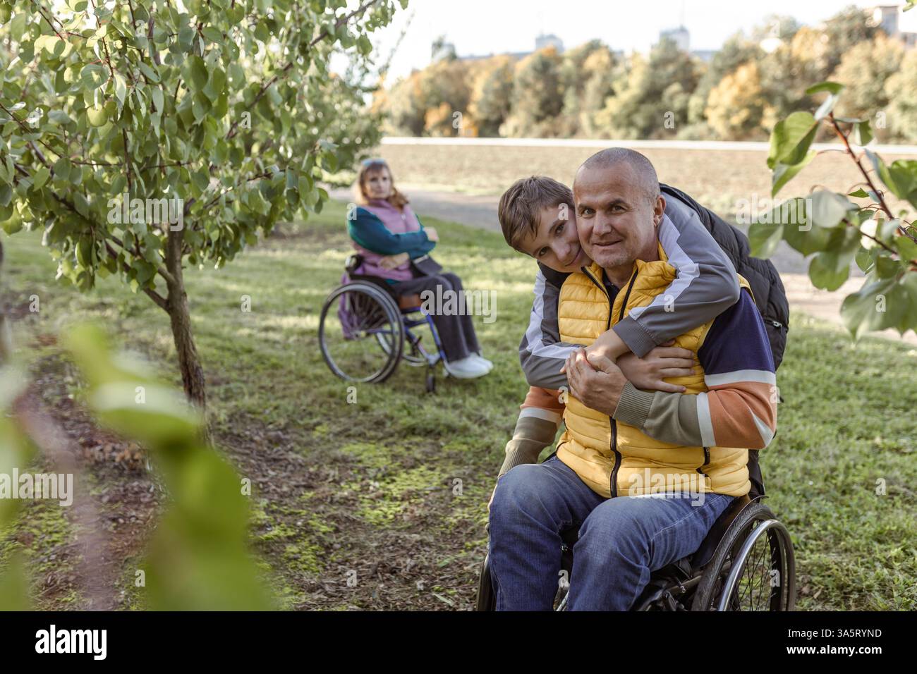 La famiglia con un figlio adolescente cammina nel frutteto Foto Stock