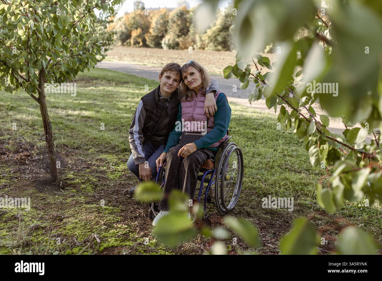 La famiglia con un figlio adolescente cammina nel frutteto Foto Stock