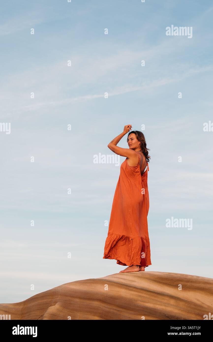 Donna che alza le braccia in un movimento simile a una danza su un'arenaria Foto Stock