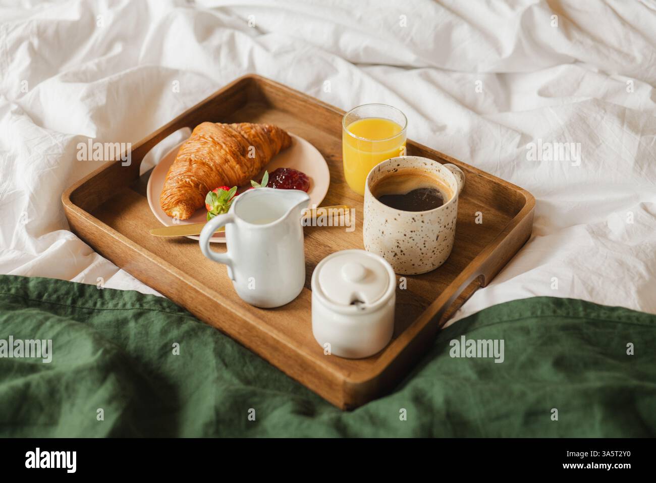 Colazione a letto - vassoio di legno con caffè, succo di frutta e croissant Foto Stock
