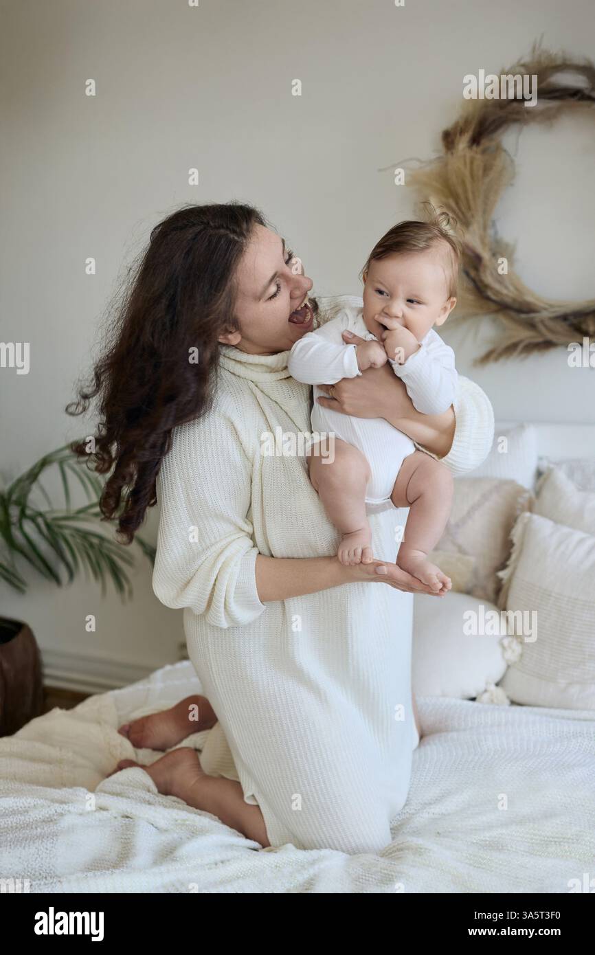 Mamma e bambino ridono insieme in un ambiente accogliente Foto Stock