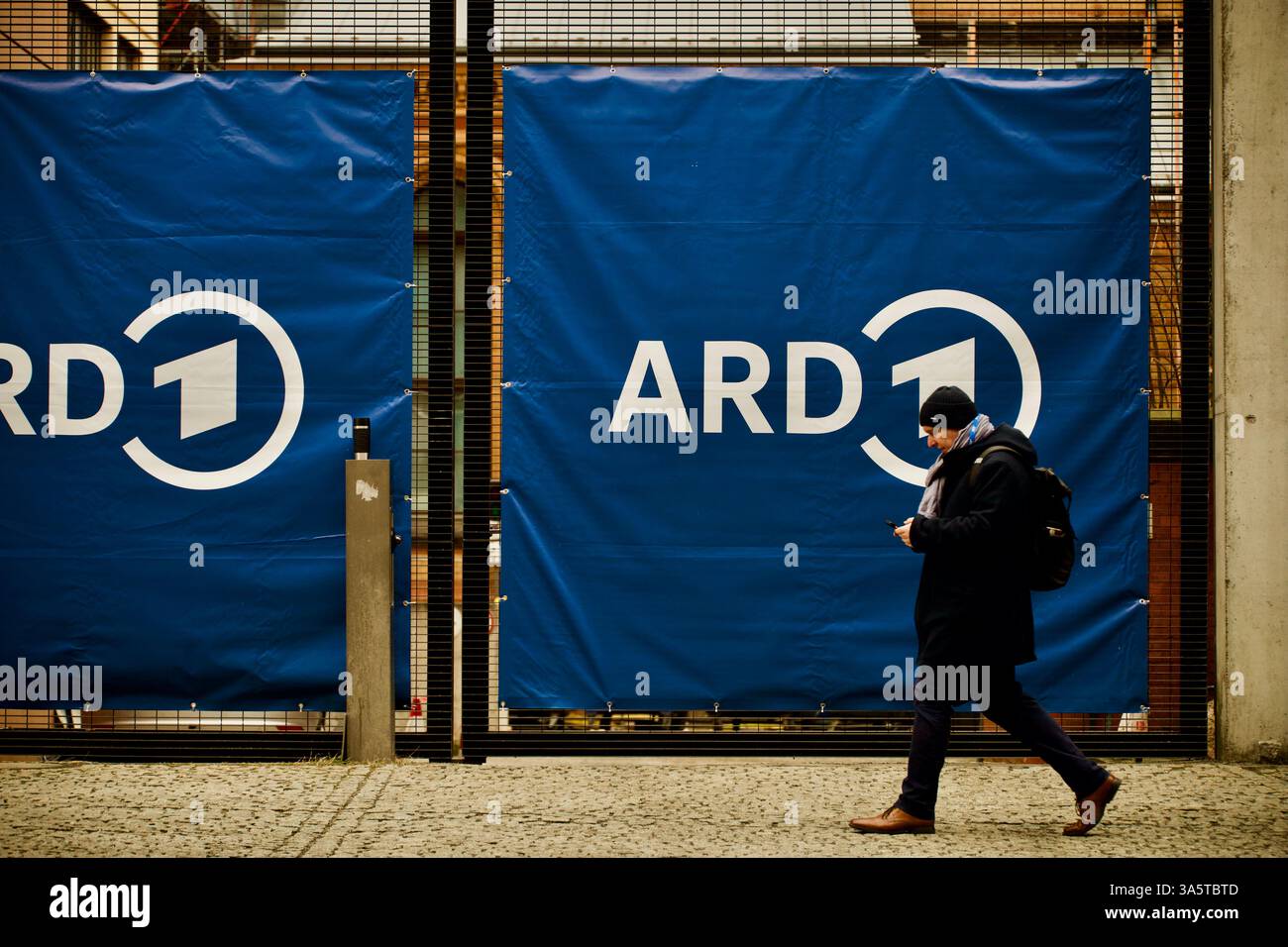 Berlino, Germania. 23 febbraio 2025. Una persona cammina per striscione ARD. Foto Stock